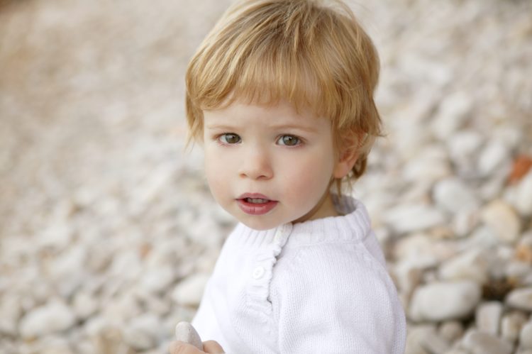 Image of beautiful blond boy portrait winter outdoor, stones background