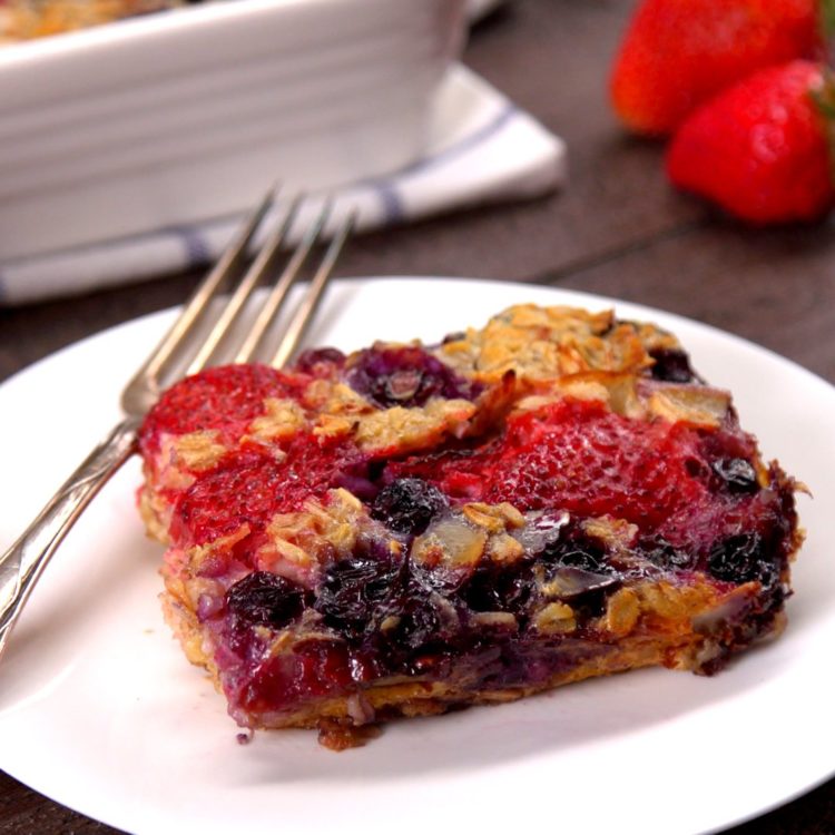 Serving of baked oatmeal with strawberries and blueberries on plate.