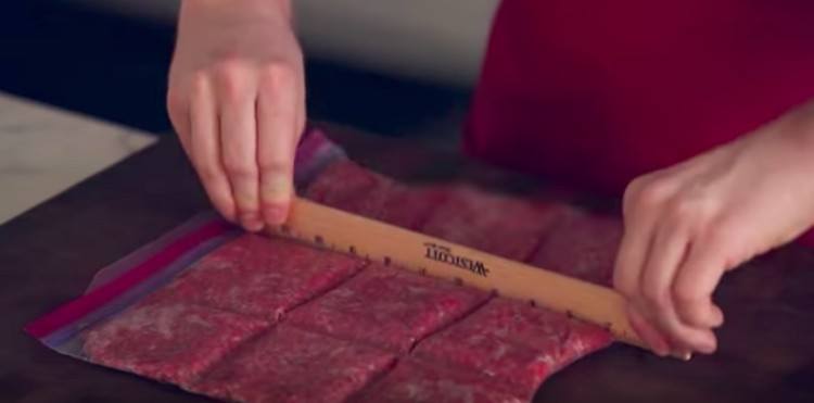 man uses ruler to portion ground beef