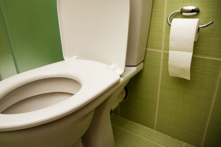Toilet in green tiled bathroom.