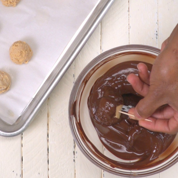 Dipping peanut butter cheesecake ball in melted chocolate