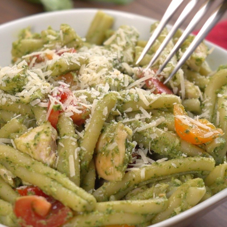 Eating pasta mixed with pesto sauce of avocado and garlic