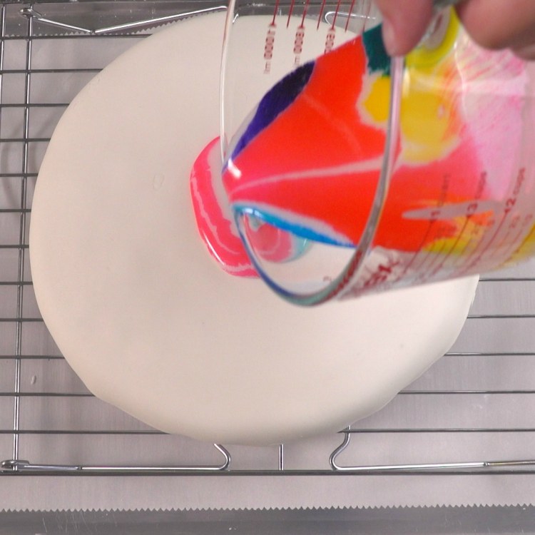 Beginning to pour tie dye glaze on fondant-covered cake