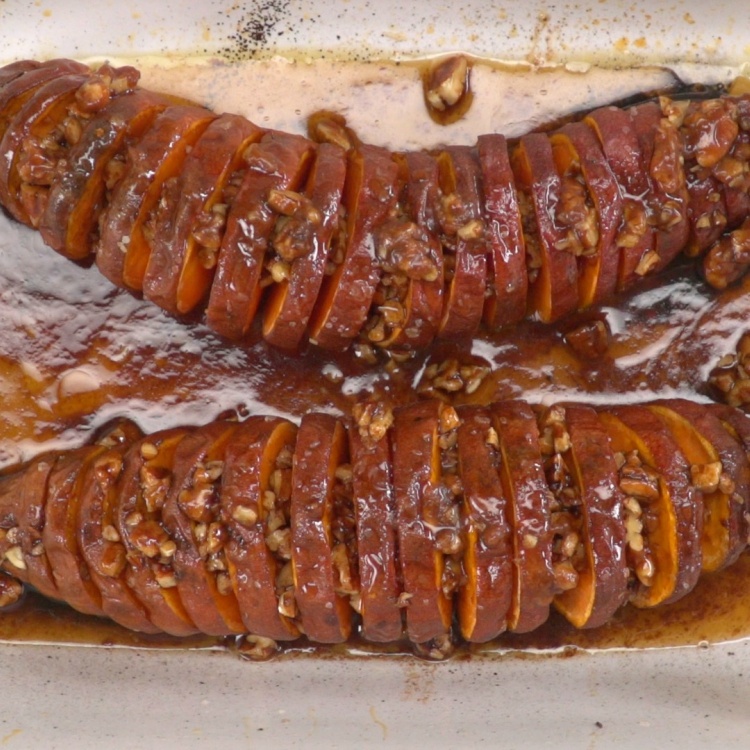 Hasselback-cut sweet potatoes filled with maple pecan glaze in pan