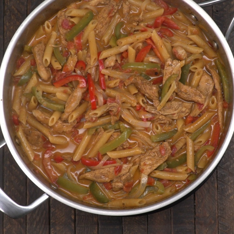 Chicken fajita pasta cooking in sauté pan with sauce
