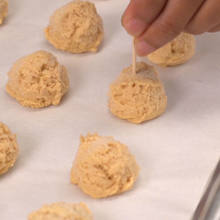 Balls of peanut butter cream cheese mixture being pierced with toothpick