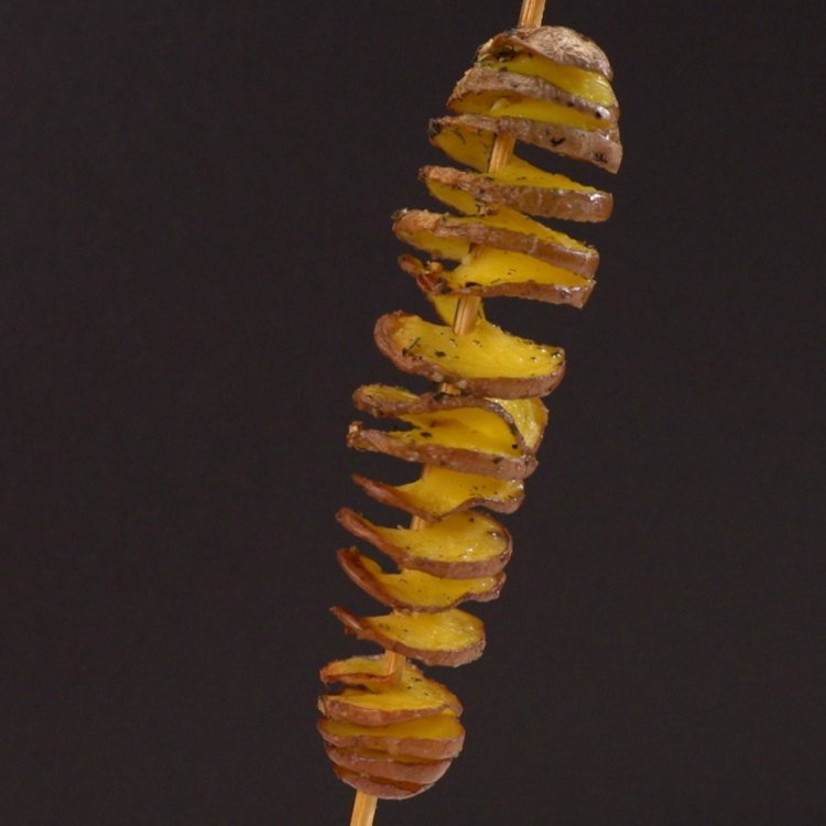 Skewer potato in tornado spiral on black background