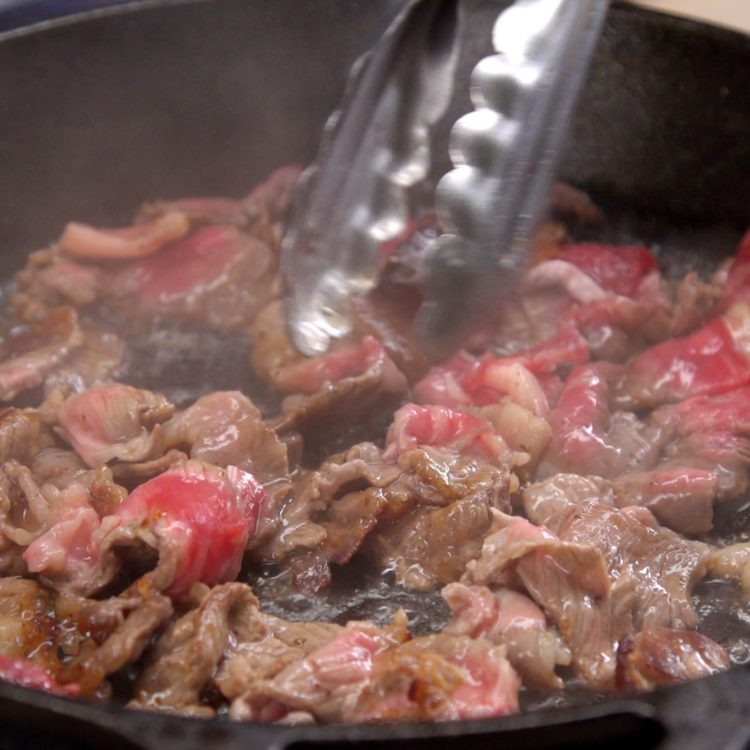 Philly Cheesesteak Sliders sauteeing the thinly sliced ribeye steak