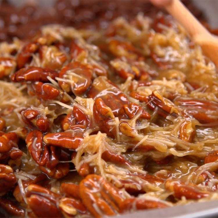 Pecan halves mixed with eggs, brown sugar, corn syrup, butter and shredded coconut
