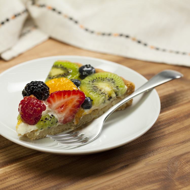 sugar cookie fruit tart slice on plate with fork