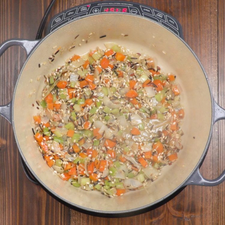 Creamy chicken and wild rice soup ingredients in pot.