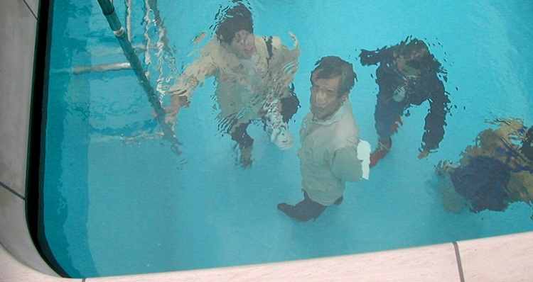 Looking down into swimming pool art at man with cell phone