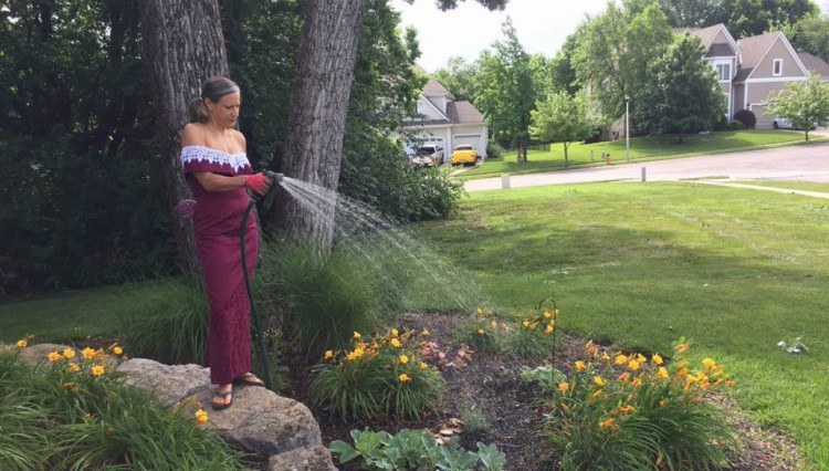 Image of woman in gown watering flowers.