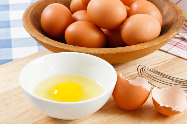 basket of brown eggs with raw egg