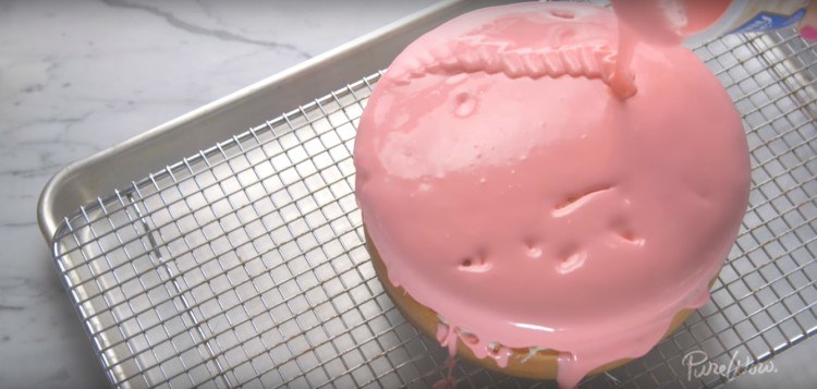 Pouring melted frosting onto cake.