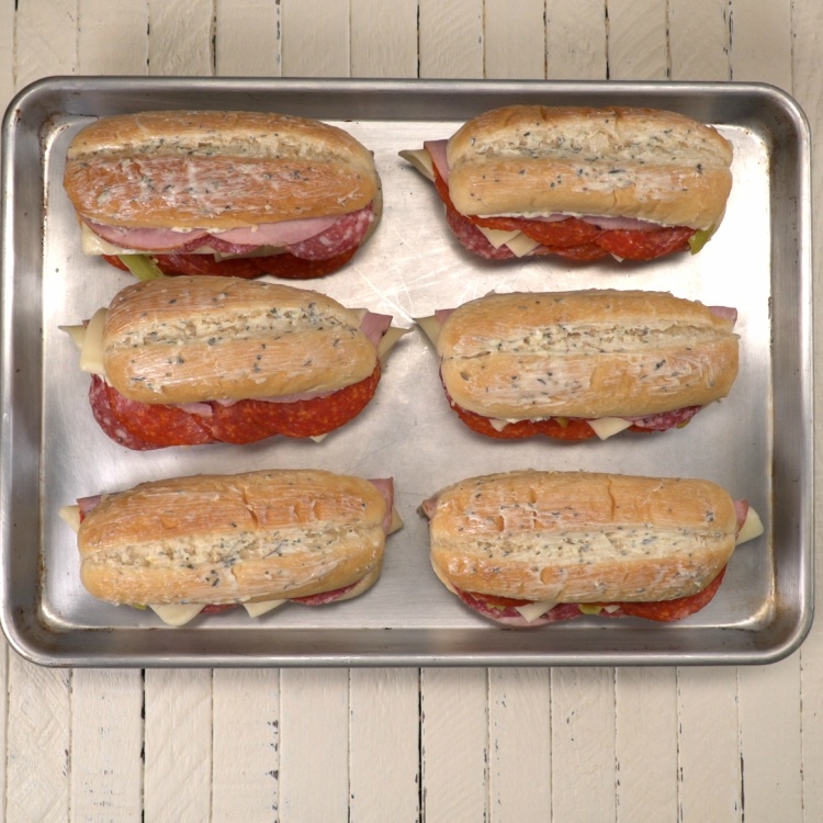 Italian sandwiches spread with garlic herb butter before baking